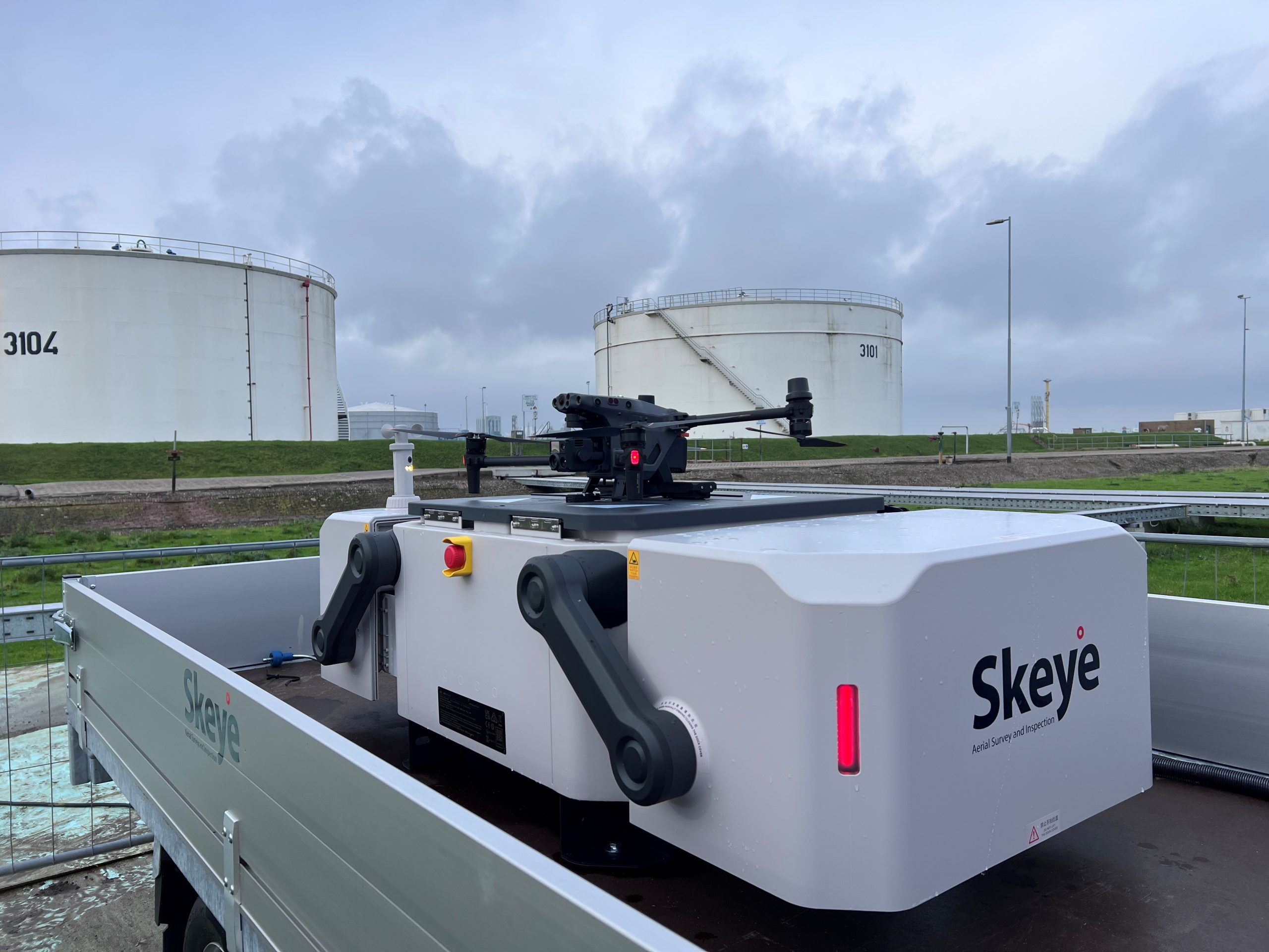 Drone-in-a-Box system open with drone inside, used for remote BVLOS operations by Skeye near industrial tanks.
